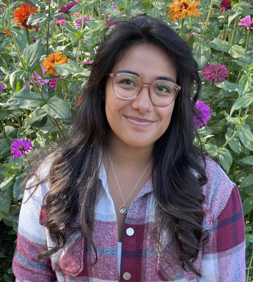 Yasmin M. photographed in front of a flower garden