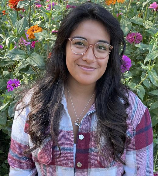Yasmin M. photographed in front of a flower garden
