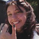 A close up picture of Ellie smiling and holding a "thumbs up"