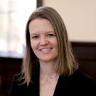 Smiling woman with shoulder-length brown hair wearing black blazer in office