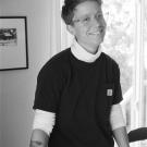 Black and white photograph of a smiling person wearing a black shirt and white turtleneck.
